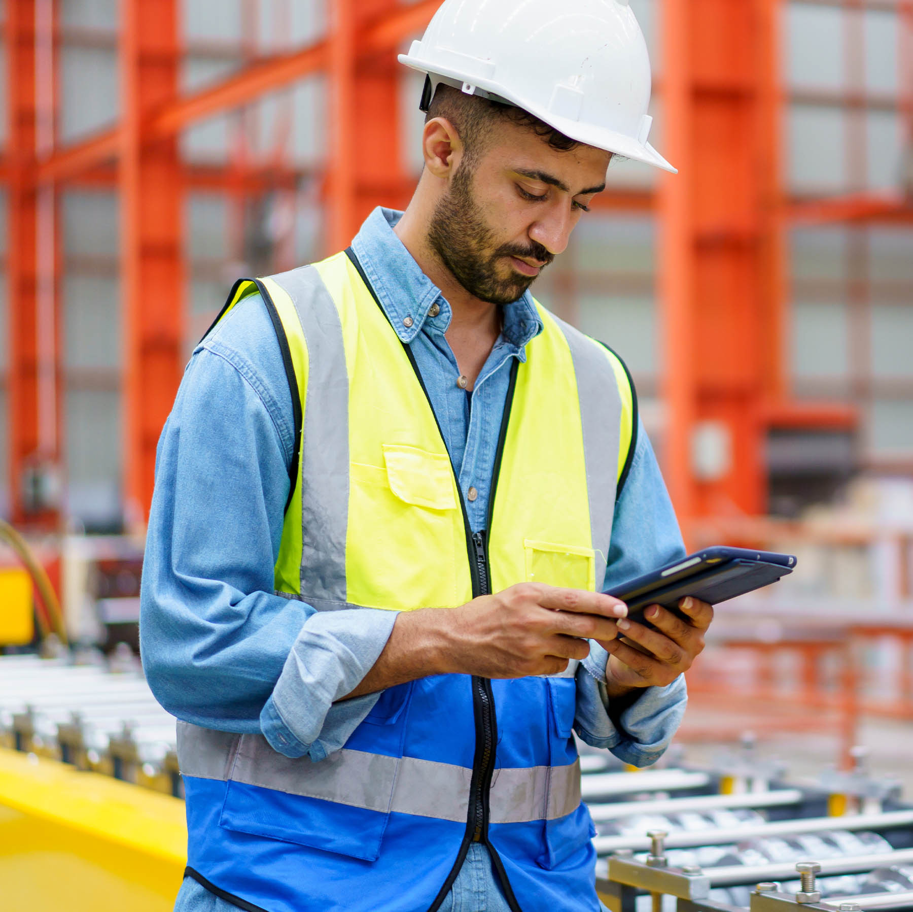 Latin American man in factory setting using an iPad