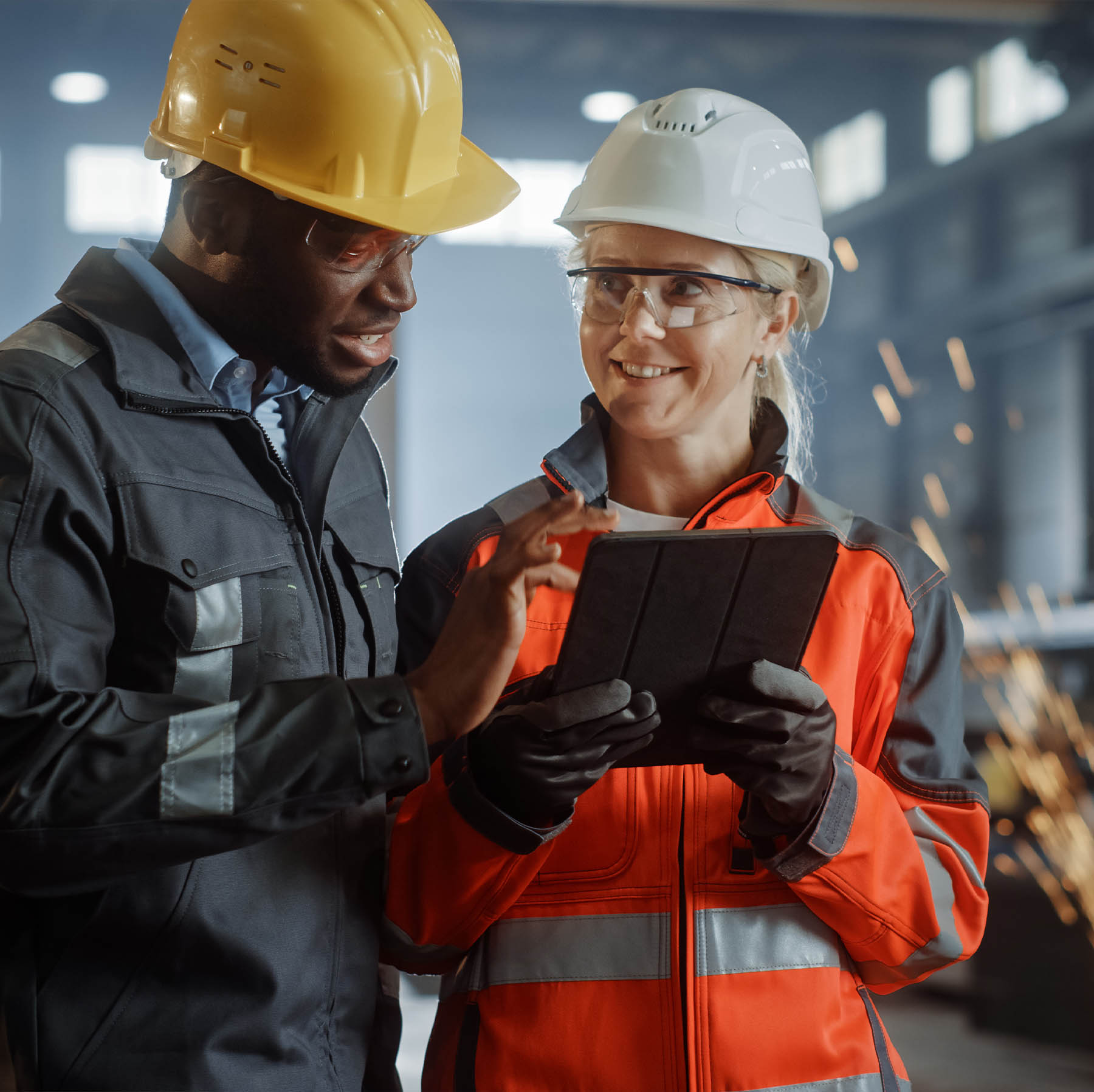 African American man and caucasian woman in factory setting using an iPad